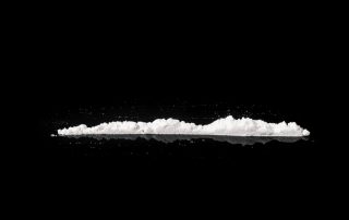 Una ratlla de cocaïna obre fons negre, representant l'addicció