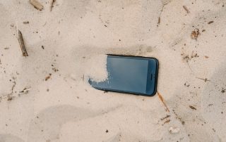 Representació de desconnexió digital: un mòbil enterrat a la sorra de la platja