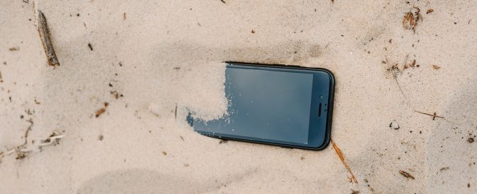 Representació de desconnexió digital: un mòbil enterrat a la sorra de la platja