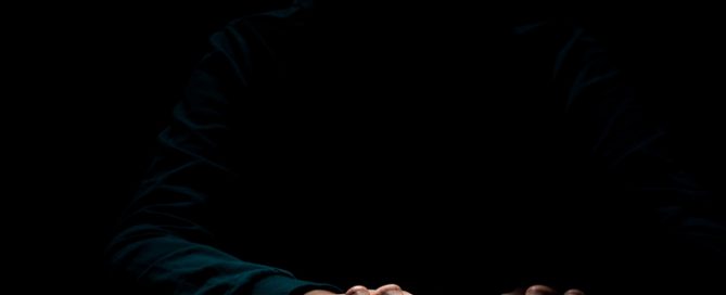 Mans sobre un teclat d'ordinador en un ambient fosc